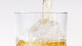 Apfelsaft in ein Glas mit Eiswürfeln gießen (Close Up)