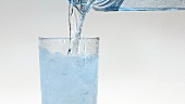 Wasser in ein Glas mit Crushed Ice gießen