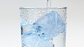 Wasser in ein Glas mit Eiswürfeln gießen (Close Up)