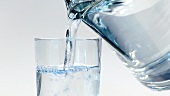 Wasser aus der Kanne in ein Glas gießen