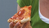 Young woman biting into a slice of pizza