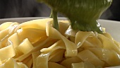 Spooning pesto onto ribbon pasta