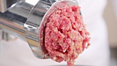 Putting minced meat and vegetable mixture through mincer