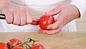 Tomate von der Rispe nehmen und kreuzweise einritzen