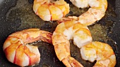 Frying prawns in a pan and scattering them with salt