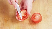 Gewaschene Tomate halbieren und den Stielansatz entfernen