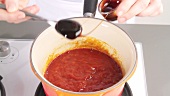 Dark syrup being added to barbecue sauce