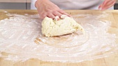 Pastry being kneaded on a floured work surface