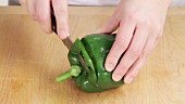 A pepper having its top cut off and being halved