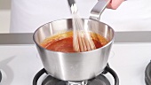 Boiling barbecue sauce being stirred and then removed from the heat