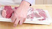 Cling film being removed from New York strip steaks