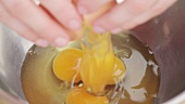 Eggs being cracked into a metal bowl