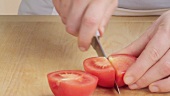 The stem being removed from a tomato and quartered
