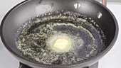 A piece of butter being melted in a pan