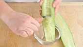 Cucumber seeds being scooped out with a spoon