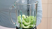 Sliced cucumber being placed in a blender