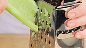 Half a cucumber being grated (close-up)
