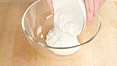 Natural yogurt being poured into a bowl