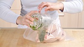Garlic and herb marinade being added to chicken in a freezer bag