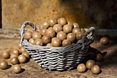 Unshelled macadamia nuts in and beside a wicker basket