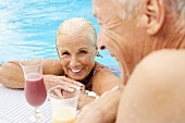 Germany, senior couple drinking cocktail at pool