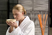 Germany, young woman holding tea bowl, close-up