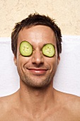 Germany, young man with cucumber slices on eyes