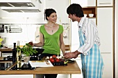 Young couple cooking food in kitchen, smiling