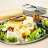 Cheese platter with savoury snacks and grapes