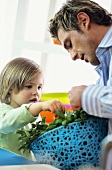 Father and son examining fresh herbs in kitchen
