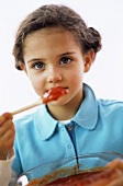 Girl (4-7) tasting tomato sauce, close-up, portrait