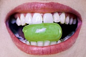 Woman holding grape between teeth, close-up