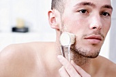 Man massaging face with brush, close-up