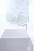 Tisch mit pastellblauer Tischdecke; dahinter ein modernes Gemälde