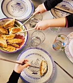 Kinder essen asiatische Teigtaschen mit Stäbchen
