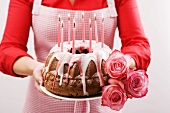 Frau hält Napfkuchen und Rosen zum Geburtstag