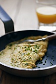 Herb omelette with chives in frying pan