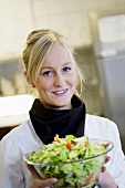 Female chef holding bowl of salad
