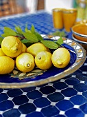 Several lemons with leaves in ceramic dish