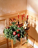 Christmas wreath decorated with apples besides candle stand
