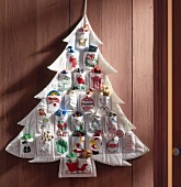 Advent calendar made of fabric in shape of Christmas tree hanging on wall