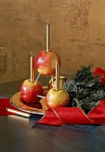 Adventsgesteck aus vier Äpfeln mit drei Goldkerzen, Tannenzweige