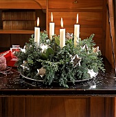 Adventsgesteck auf silbernem Tablett , vier weiße Kerzen und Silbersterne