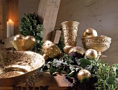Goldene Gefäße und Adventsgesteck auf Holzbalken