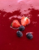 Zwei Erdbeeren und drei Brombeeren roter Sauce