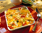 Vegetable gratin with feta cheese, fennel, carrots, potatoes and peppers on square plate