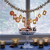 Different shapes of Christmas cookies hanging on garland in front of window