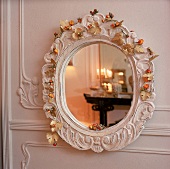 Spiegel mit altem weißem Rahmen, mit kleinen Blüten geschmueckt.
