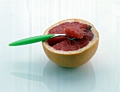 Eine halbe Grapefruit mit Löffel freigestellt