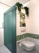 Dusche mit Glastrennwand und WC, Borte aus grünem Glasmosaik